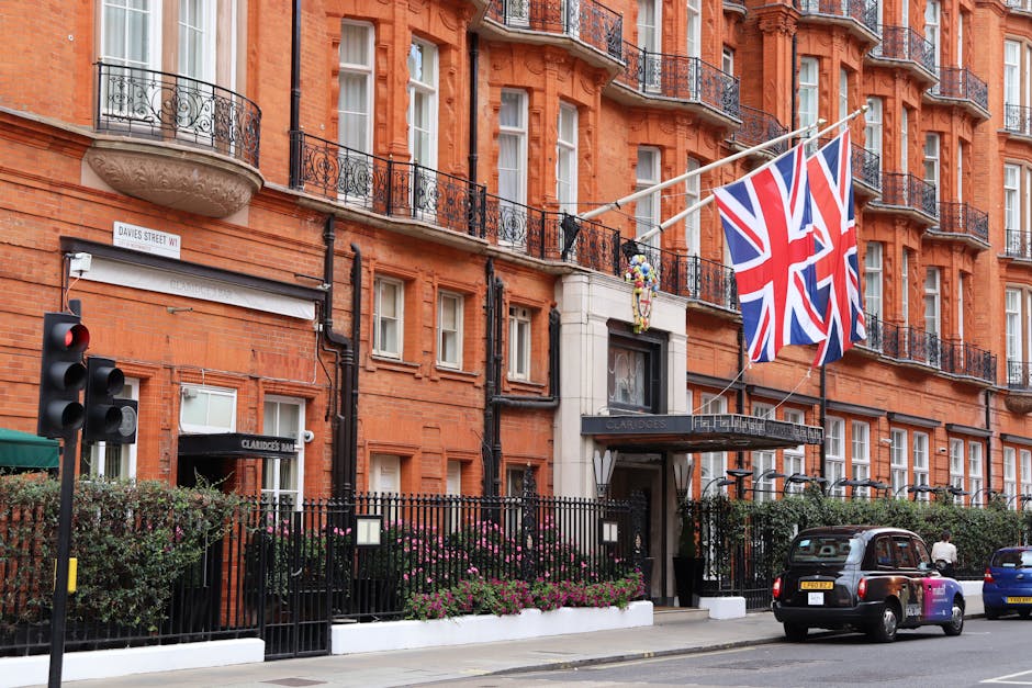 The exterior of Claridge's hotel, a large brick building featuring multiple stories with evenly spaced sash windows, decorative black wrought-iron balconies, and a stone balcony with a rounded front.